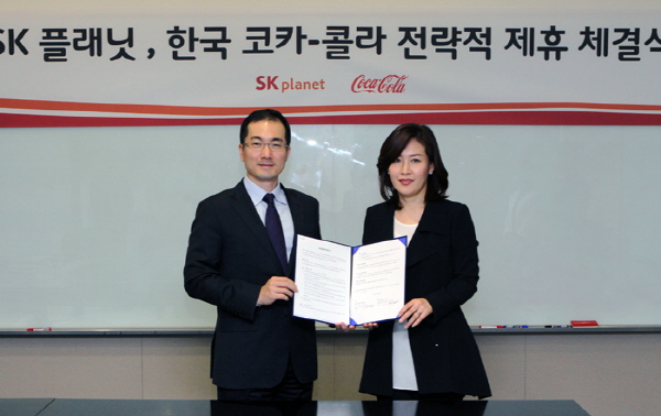 SK플래닛, 한국 코카-콜라 전략적 제휴 체결 사진입니다. 각 회사 관계자들이 기념 사진을 촬영하고 있습니다. 현수막에는 SK플래닛 한국 코카콜라 전략적 제휴 체결이라고 적혀있습니다.